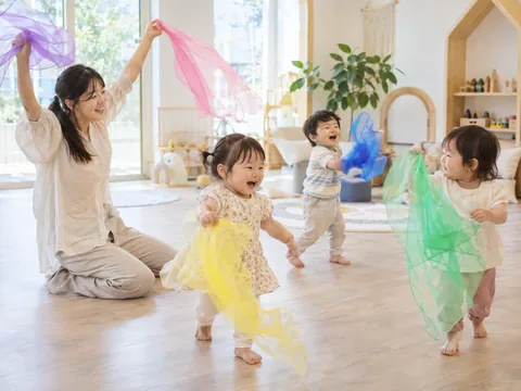 교사와 함께 색색의 스카프를 흔들며 몸으로 표현하는 아이들의 이미지