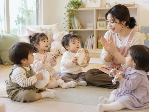 교사와 둘러앉아 탬버린과 방울 악기로 음악놀이를 하는 아이들의 이미지