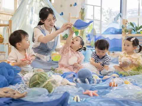 푸른 천과 바다 동물 인형, 조개 소품으로 상상놀이를 하는 아이들의 이미지